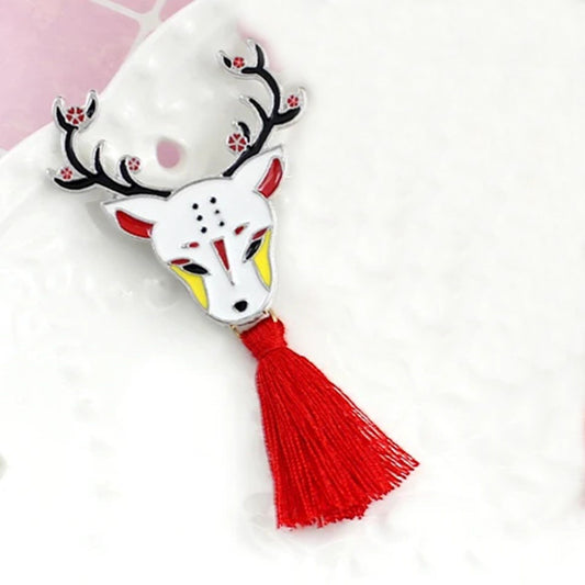 une broche en métal en forme d'un cerf représenté de façon onirique selon le folklore japonais. Il est élégant avec ces bois fleuris et son pompon rouge.