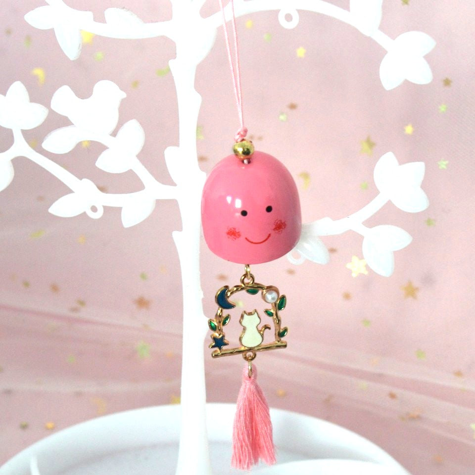 un carillon avec une clochette expression kawaii, une breloque en forme de chat qui est sur une balançoire y est suspendu, et un pompon coloré finit l'ensemble.