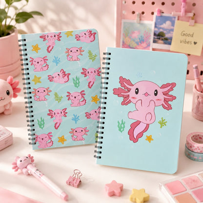 Deux carnets spirales kawaii axolotl roses sur fond bleu pastel, présentés dans un décor de bureau mignon avec papeterie rose et accessoires kawaii.