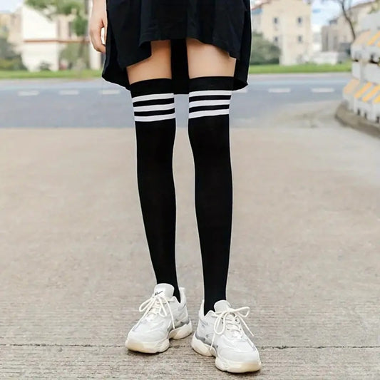 une paire de chaussettes noires hautes dont le haut présente des lignes blanches qui contrastent avec le noir de la chaussette