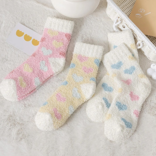 des chaussettes toutes douces et moelleuses en matière pilou réconfortantes au motif de coeurs colorés.
