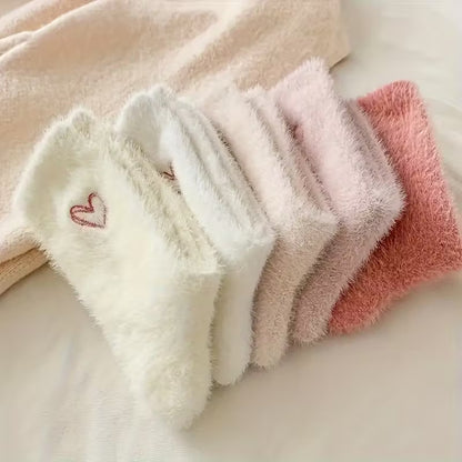 des paires de chaussettes toutes douces en matière pilou dans les tons roses et blancs. Sur le haut de la chaussette, un joli coeur rose est imprimé. Style féminin adorable, idéal pour les soirées cocooning !