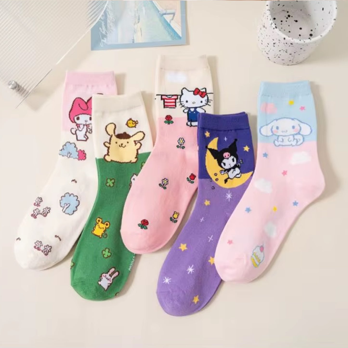 Lot de chaussettes Sanrio colorées et douces représentant les personnages Hello Kitty, Kuromi, My Melody, Cinnamoroll et Pompompurin sur fond pastel. Chaussettes confortables au style kawaii pour le quotidien.