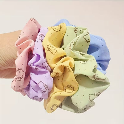 Lot de chouchous Hello Kitty colorés en tissu, tenus par une main de femme. Ces élastiques pour cheveux roses, jaunes, verts, bleus et violets apportent une touche mignonne et colorée aux coiffures du quotidien.