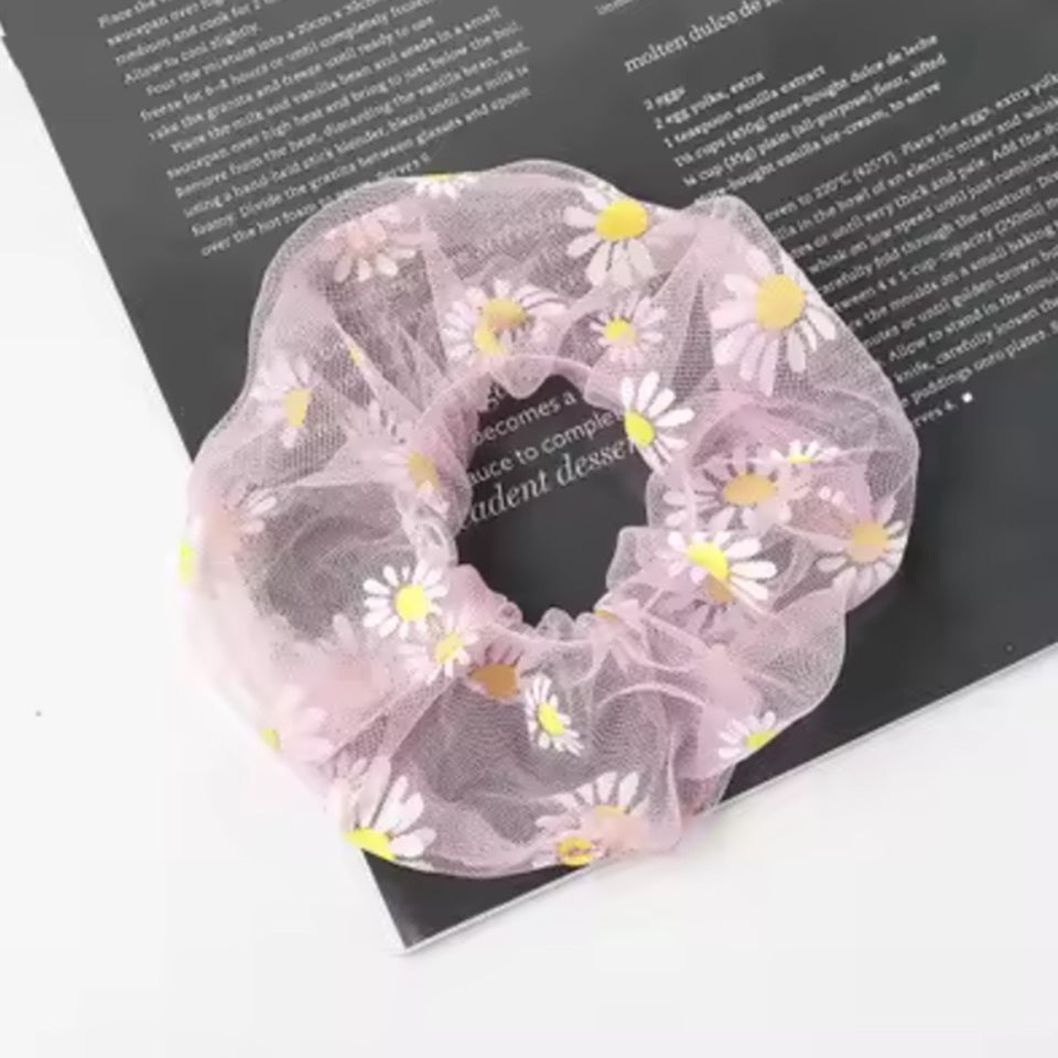 un chouchou rose joliment présenté, posé sur une feuille sur une table blanche.