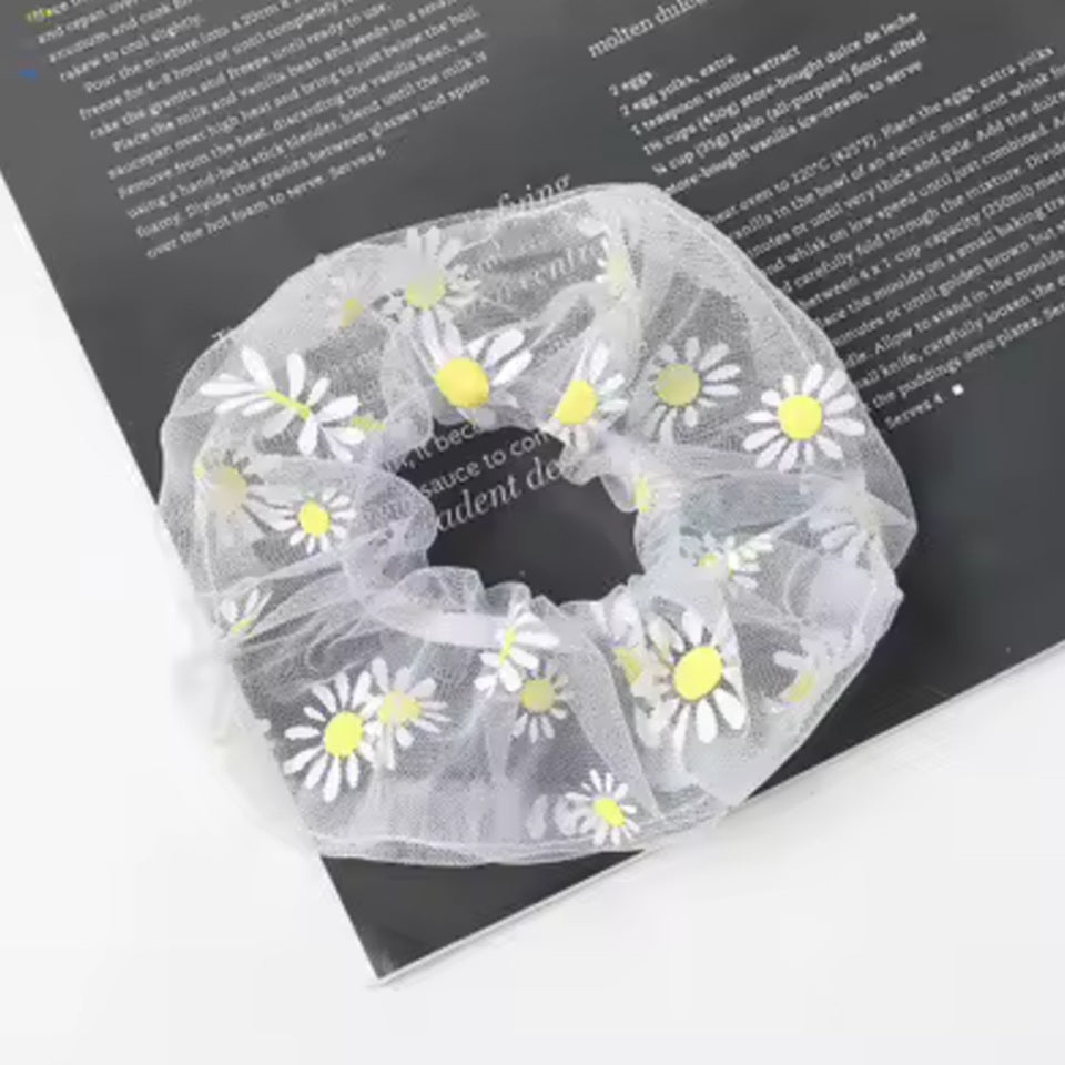 un chouchou gris joliment présenté, posé sur une feuille sur une table blanche.