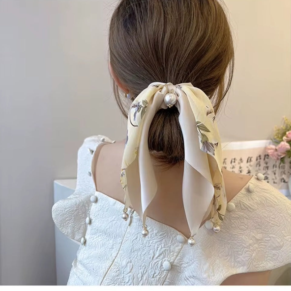 des chouchous foulards vert, beige et noir aux motifs fleuris et aux couleurs unies. De jolies perles blanches finissent de compléter l'ensemble pour un résultat féminin, romantique et élégant.