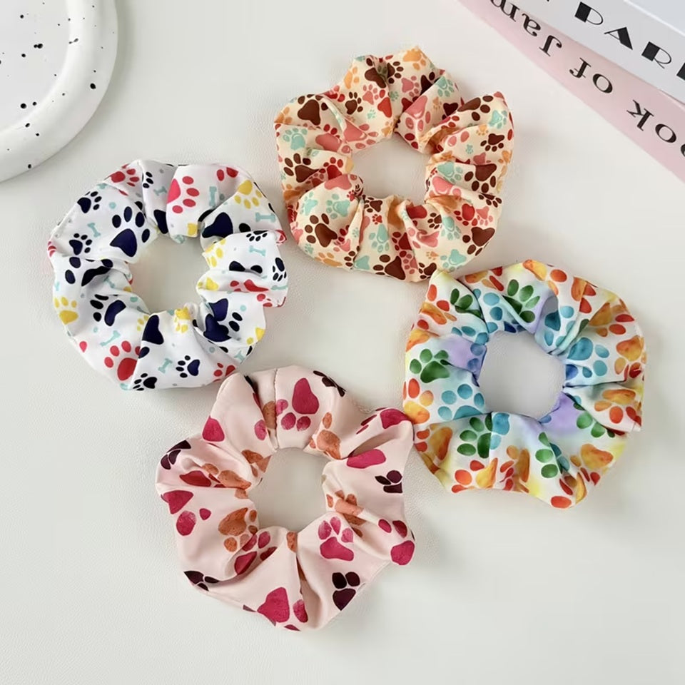 Gros plan sur 4 chouchous colorés au motif de pattes d'animaux multicolores. Design hyper mignon, parfait pour les amoureux des animaux.