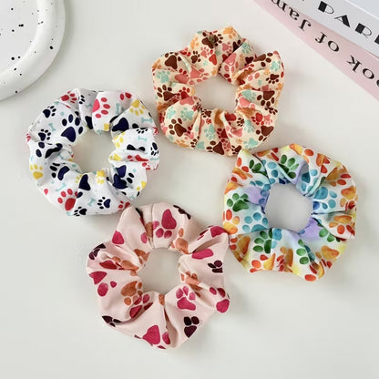 Gros plan sur 4 chouchous colorés au motif de pattes d'animaux multicolores. Design hyper mignon, parfait pour les amoureux des animaux.