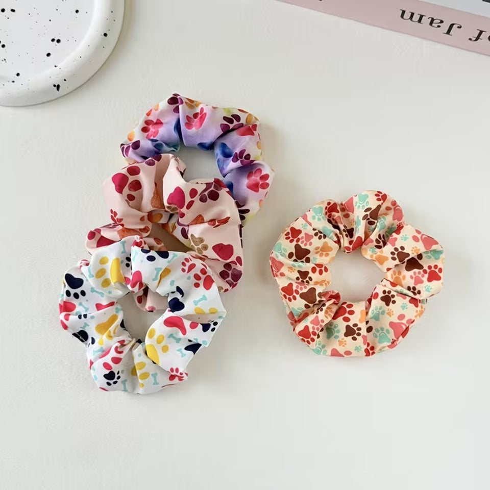 Gros plan sur 4 chouchous colorés au motif de pattes d'animaux multicolores. Design hyper mignon, parfait pour les amoureux des animaux.