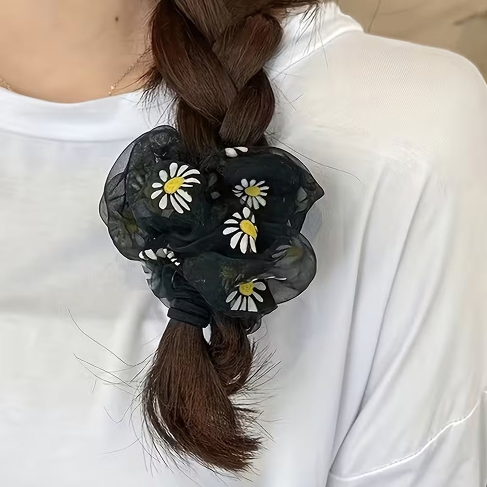 Un chouchou noir en organza au motif de marguerite qui décore une tresse. 