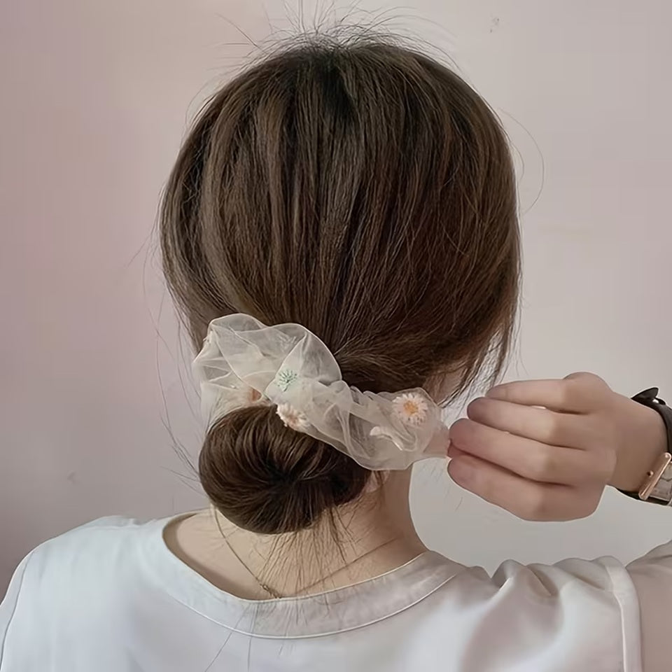 un chouchou en organza banc au motif de marguerite pour accessoiriser un chignon.