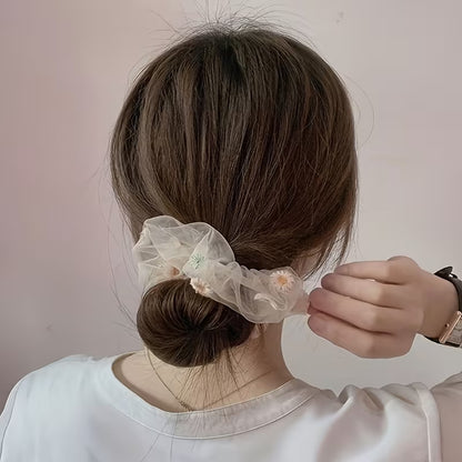 un chouchou en organza banc au motif de marguerite pour accessoiriser un chignon.