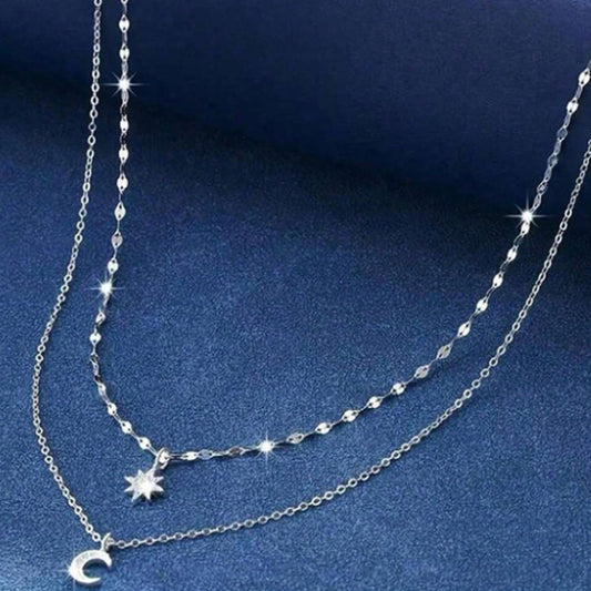 un collier composé de deux chaines argentées et de deux pendentifs tout en strass : une étoile et une lune.
