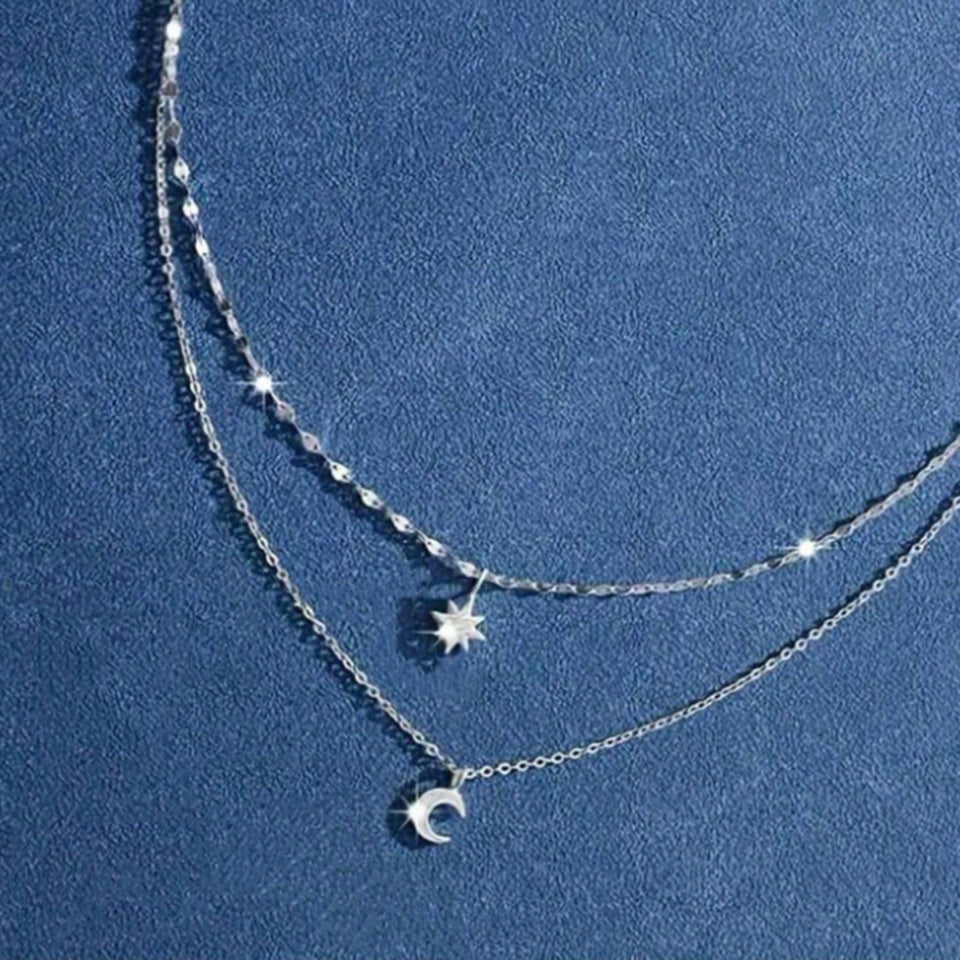 un collier composé de deux chaines argentées et de deux pendentifs tout en strass : une étoile et une lune.