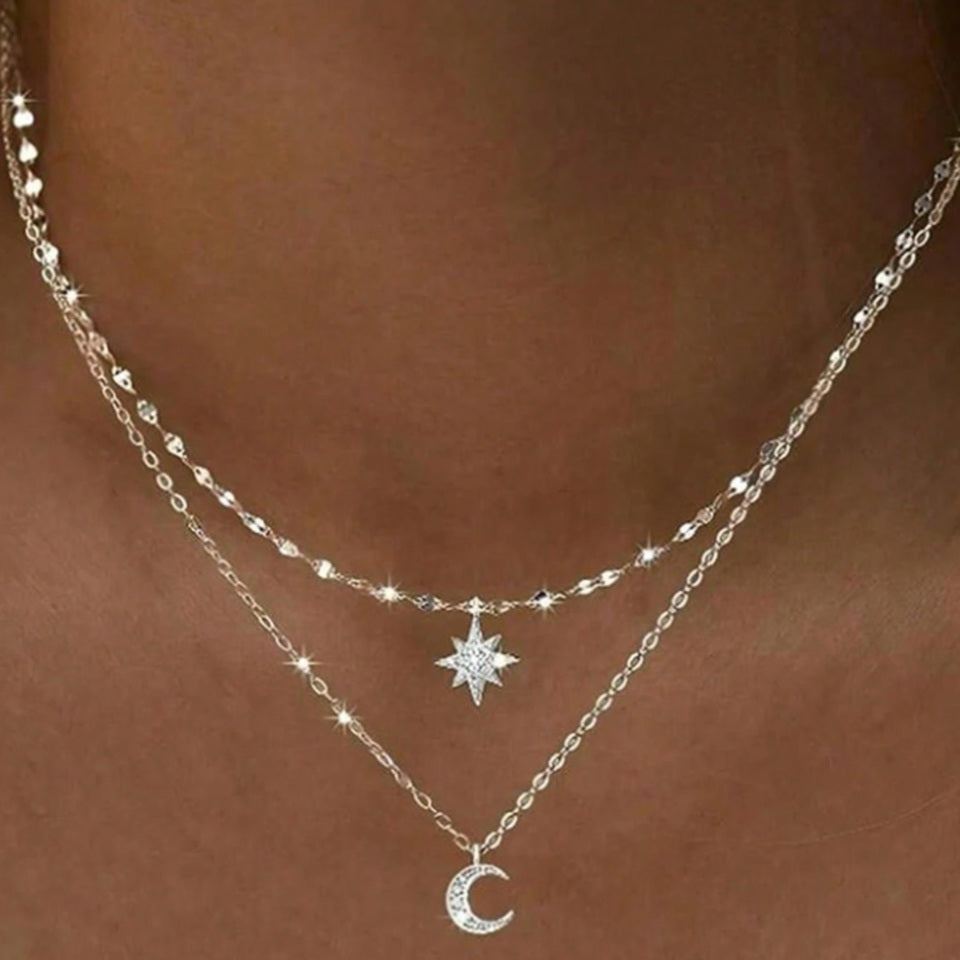 un collier composé de deux chaines argentées et de deux pendentifs tout en strass : une étoile et une lune.