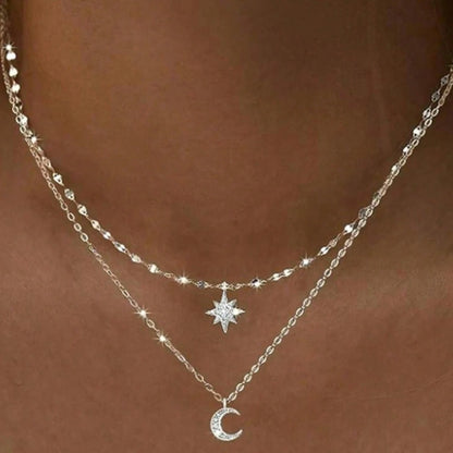 un collier composé de deux chaines argentées et de deux pendentifs tout en strass : une étoile et une lune.