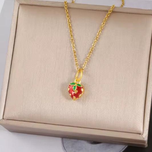 un collier doré avec un pendentif en forme de petite fraise rouge mignonne et gourmande