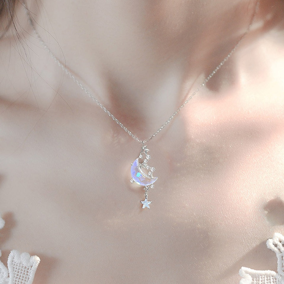 un bijou argentée dont le pendentif représente un croissant de lune aux reflets bleutés cristallins entourée de petites étoiles scintillantes