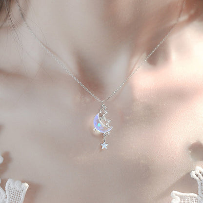 un bijou argentée dont le pendentif représente un croissant de lune aux reflets bleutés cristallins entourée de petites étoiles scintillantes