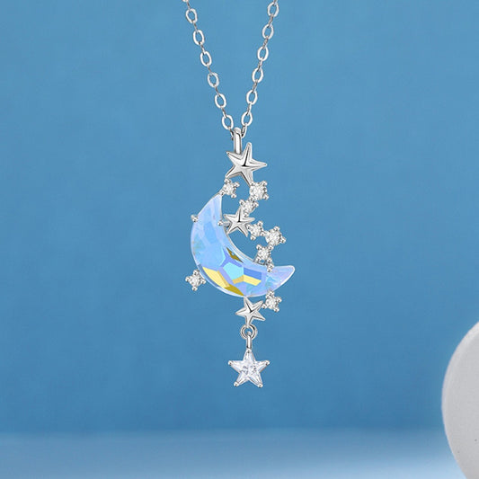 un bijou argentée dont le pendentif représente un croissant de lune aux reflets bleutés cristallins entourée de petites étoiles scintillantes