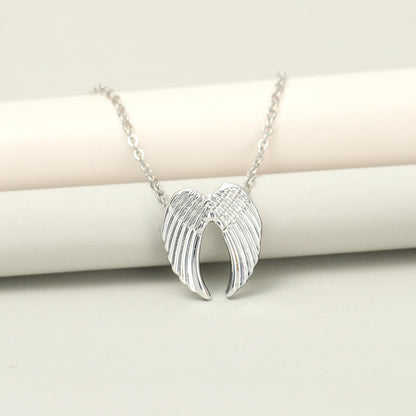 un collier argenté dont le pendentif représente une paire d'ailes d'anges délicatement sculptées.