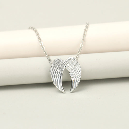 un collier argenté dont le pendentif représente une paire d'ailes d'anges délicatement sculptées.