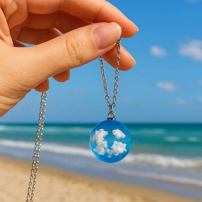 un joli collier argenté d'une sphère transparente et bleue renfermant des nuages comme si un bout d eciel y avait été capturé.