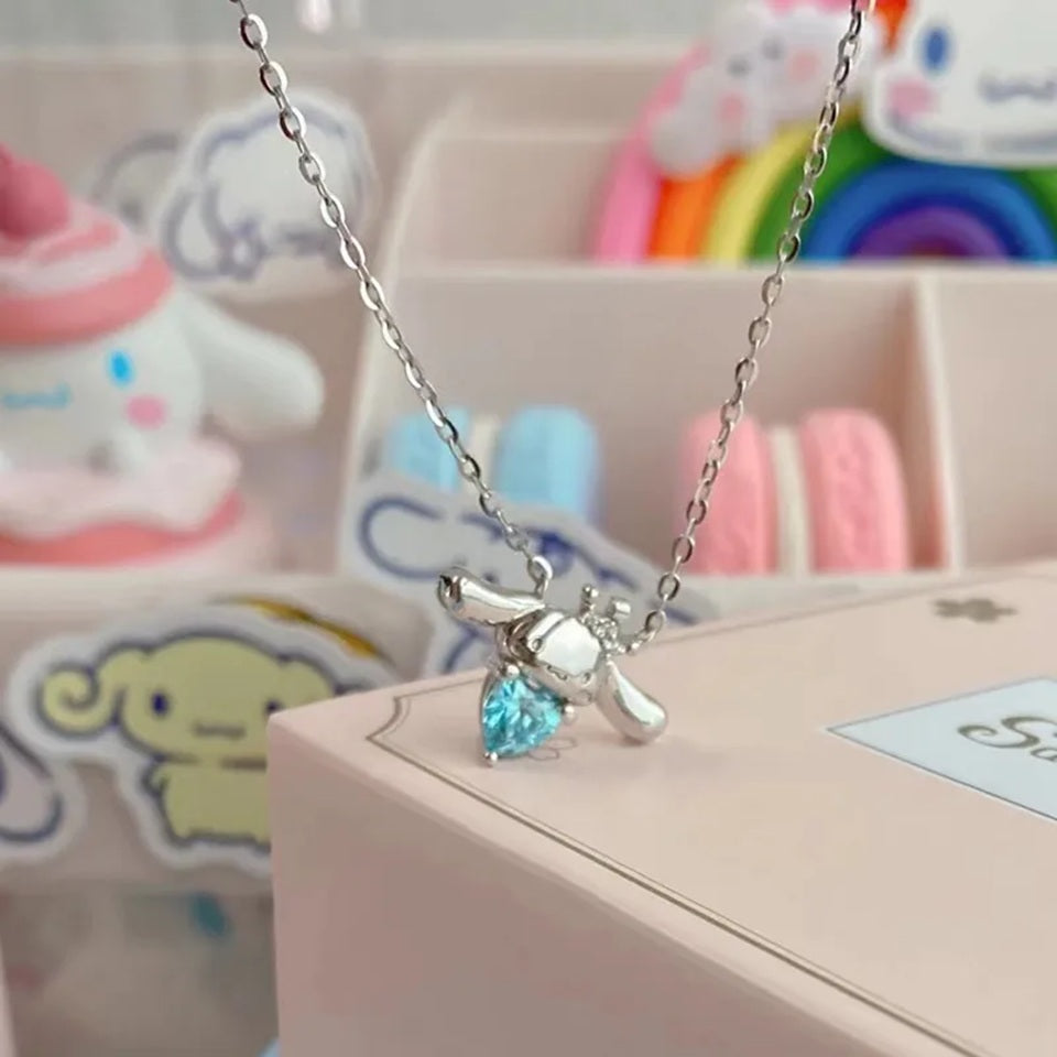 un superbe collier en alliage représentant Cinnamoroll, le petit chien de Sanrio qui tient un strass bleu en forme de coeur dans ses pattes. En coloris argenté, il apporte fraicheur et charme tout en discrétion.