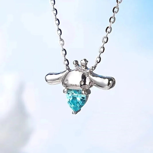 un superbe collier en alliage représentant Cinnamoroll, le petit chien de Sanrio qui tient un strass bleu en forme de coeur dans ses pattes. En coloris argenté, il apporte fraicheur et charme tout en discrétion.