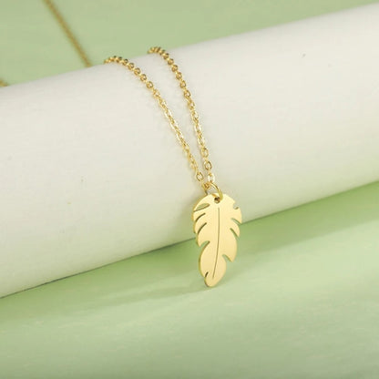 un collier doré dont le pendentif représente une petite plume. Symbole de liberté et de légèreté