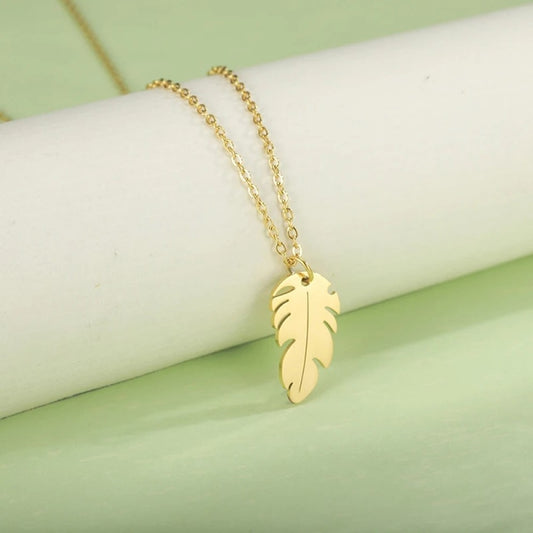 un collier doré dont le pendentif représente une petite plume. Symbole de liberté et de légèreté
