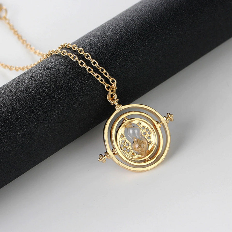 un collier doré reprenant la forme et le design du fameux retourneur de temps, le collier d'Hermione dans Harry Potter. Il y a un sabler, des anneaux rotatifs.