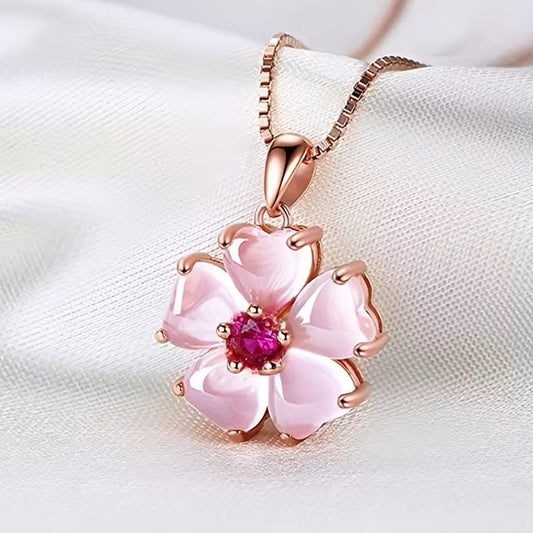 un superbe collier rose gold dont le pendentif est une jolie fleur de sakura aux pétales roses et dont le coeur est un strass rose brillant. Le bijou est élégant et romantique et rappelle la saison des sakura en fleurs au Japon.