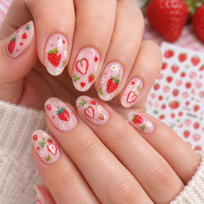 Gros plan sur les mains d’une femme portant une manucure rose nude décorée de stickers nail art fraise kawaii : petites fraises rouges, fraises coupées, fleurs blanches, feuilles vertes et petits cœurs. Ces autocollants pour ongles aux motifs fruités et gourmands créent une manucure fraîche, romantique et adorable. Faciles à appliquer, ils sont parfaits pour personnaliser ses ongles avec une touche de fantaisie.