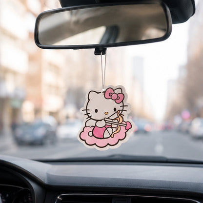 un désodorisant en forme de hello kitty habillé en cupidon, avec un arc et une flèche coeur suspendu à un rétroviseur intérieur d'une voiture, qui roule sur une route de ville.