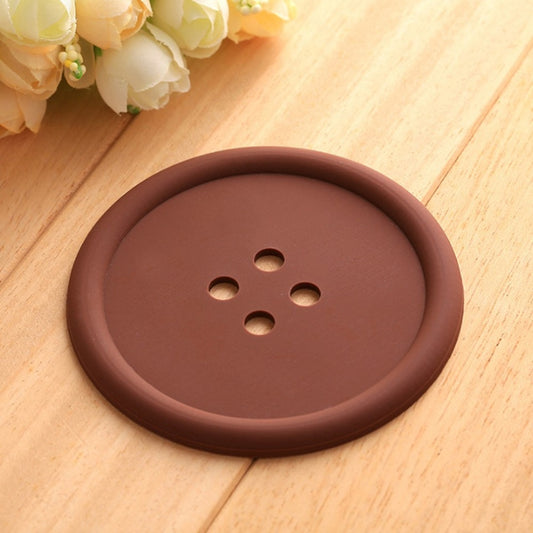un dessous de verre en forme de bouton marron. Très rigolo et fun, il protège vos surfaces des éclaboussures