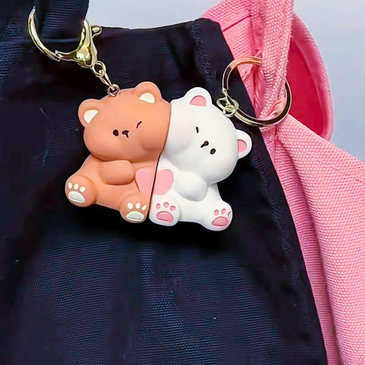 un double porte-clés composé de deux adorables oursons, un brun et un blanc, collés l'un à l'autre par un aimant; Ils partagent un coeur rose. On peut les séparer puis les réunir.