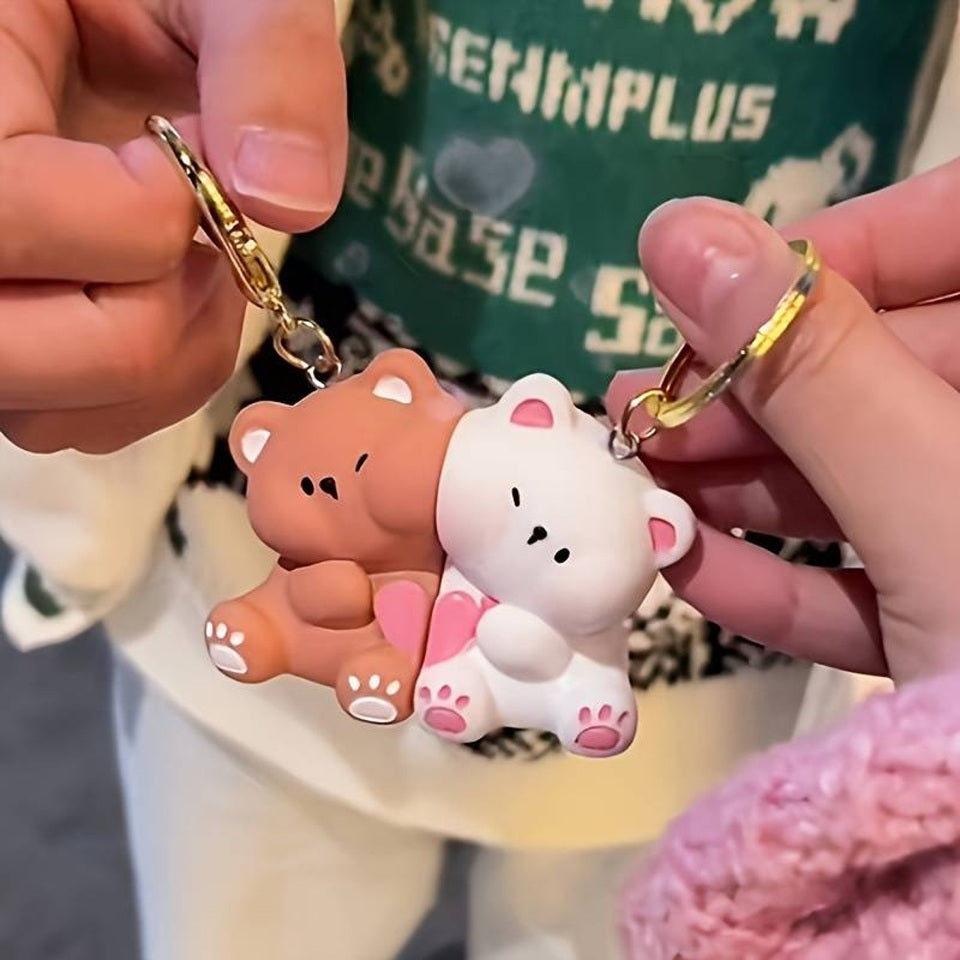 un double porte-clés composé de deux adorables oursons, un brun et un blanc, collés l'un à l'autre par un aimant; Ils partagent un coeur rose. On peut les séparer puis les réunir.