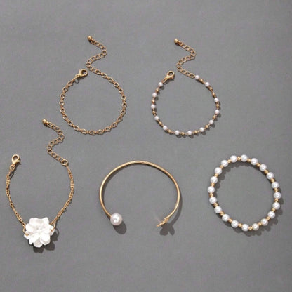 un ensemble de bracelets dorés avec des perles blanches et une fleur blanche. Style bohème, chic et élégant. 