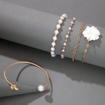 un ensemble de bracelets dorés avec des perles blanches et une fleur blanche. Style bohème, chic et élégant. 