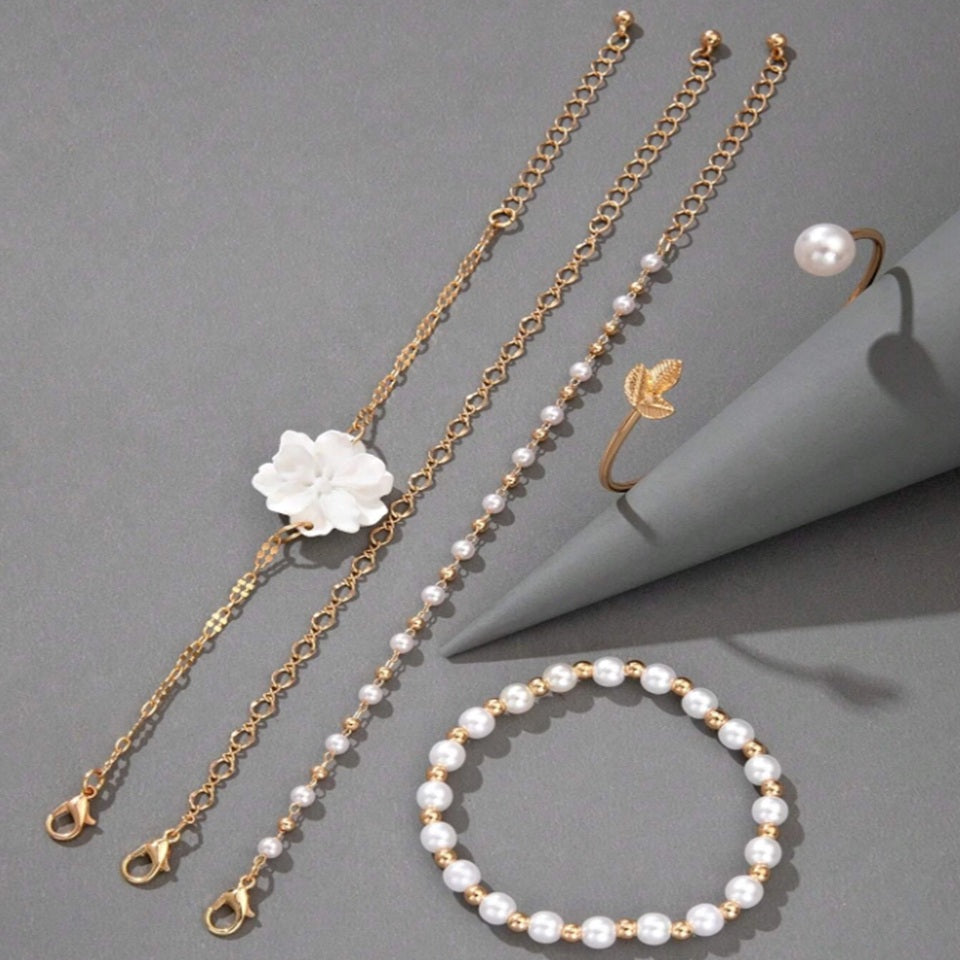 un ensemble de bracelets dorés avec des perles blanches et une fleur blanche. Style bohème, chic et élégant. 