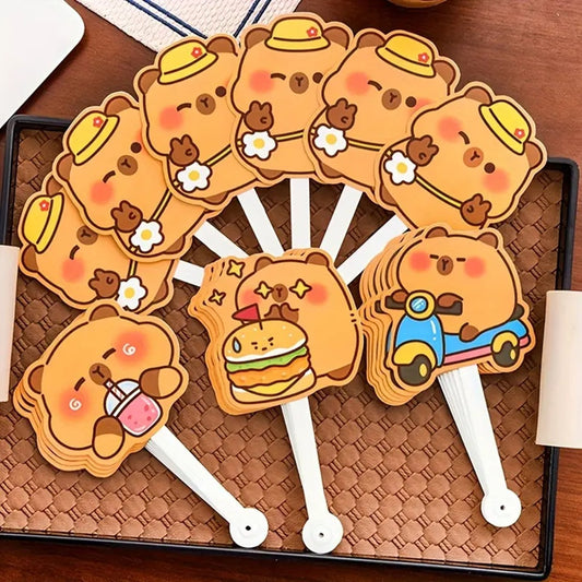 des éventails hyper rigolos et fun dont les lames sont des capybaras dans différentes situations amusantes : devant un hamburger, en scooter, en train de boire ou tout simplement content. 
