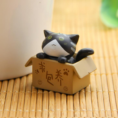 des figurines de chat bien lovés dans leur boite en carton : gris, noir, blanc ou roux, ils sont adorables. Parfait pour décorer une pièce avec style et mignonnerie