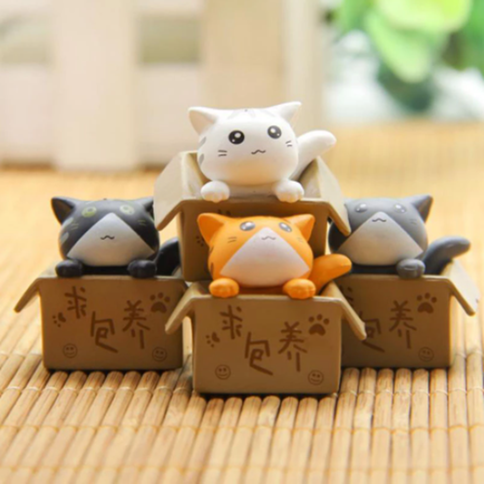 des figurines de chat bien lovés dans leur boite en carton : gris, noir, blanc ou roux, ils sont adorables. Parfait pour décorer une pièce avec style et mignonnerie