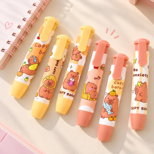 Six gommes rétractables kawaii Capybara aux étuis jaune pastel et rose pêche, décorées de capybaras mignons et colorés. Posées à plat sur un bureau clair près d’un carnet rose, ces gommes à bouton-poussoir sont des accessoires de papeterie pratiques et adorables.