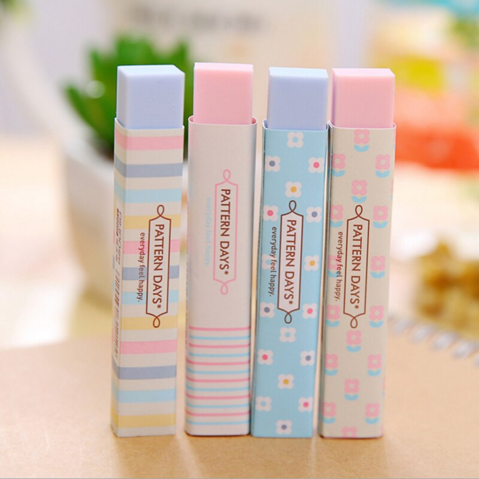 Quatre jolies gommes rectangulaires rose et bleu au motif de lignes colorées et de fleurs blanches vues de face, posées sur un bureau.