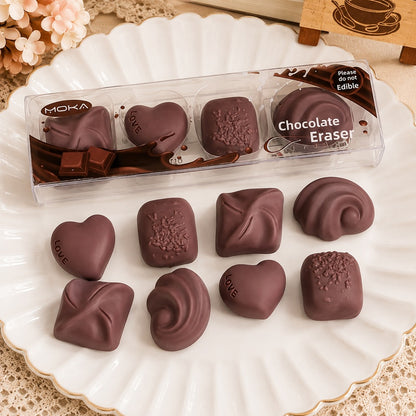Lot de 4 gommes en forme de chocolats, présentées dans une boîte transparente façon assortiment de pralines, papeterie kawaii originale et gourmande.