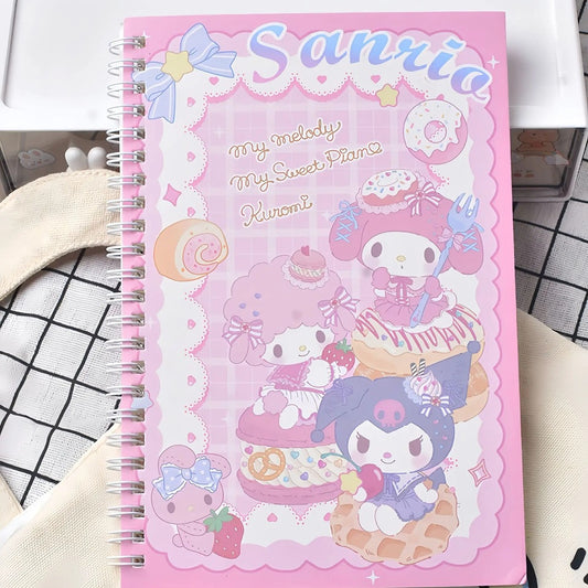 un grand carnet à spirales Sanrio mettant en scène Kuromi, My Melody et My sweet piano. Elles sont sur une gaufre, un macaron et un donut L'ensemble est hyper gourmand et kawaii dans les tons de rose blanc et bleu