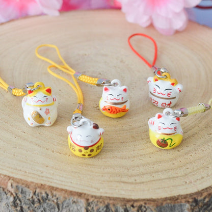des porte-clés en forme de maneki neko sous forme de grelot. Il y a plusieurs couleurs et designs différents. 